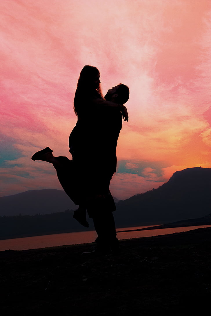 silhouette photo of man carrying woman near mountain