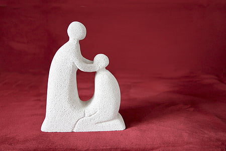 standing human and kneeling human figurine on red textile
