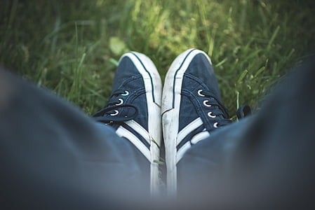 selective focus photograph of person wearing black-and-white shoes on grass