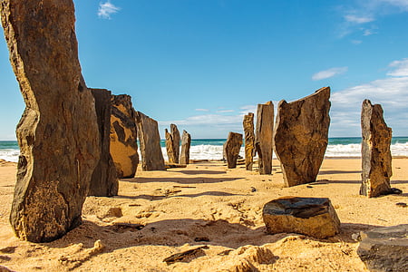 stone standing on sand near ocean during daytime