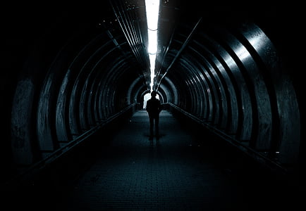 silhouette of person standing inside tunnel