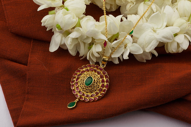 round gold-colored medallion pendant on top of brown fabric sheet