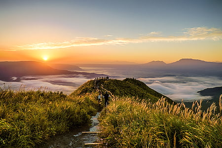 pathway between grass leading to a mountain top with an overview of sea of clouds during sunset