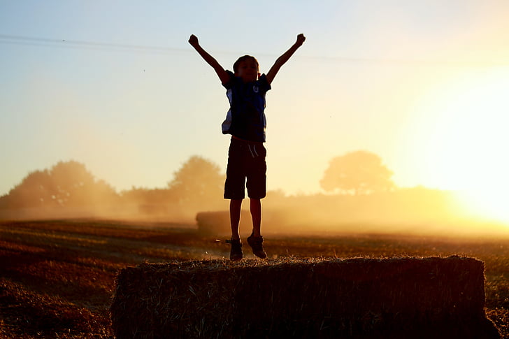 silhouette of jumping boy on green field