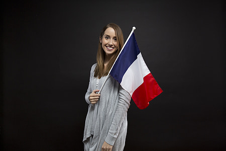 woman wearing gray cardigan holding red, blue, and white flag