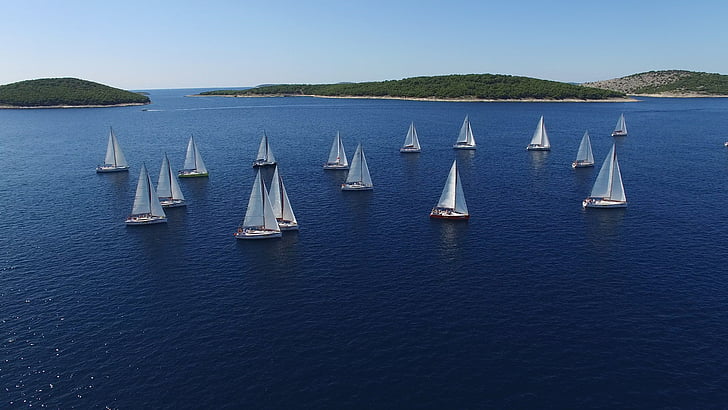 aerial view photography of white sailboats at sea surrounded by islands under clear sky during daytime