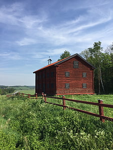 reddish-brown barn on grass field under white clouds\