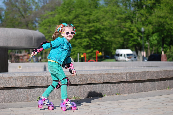 girl in blue jacket and green pants skating near fountain