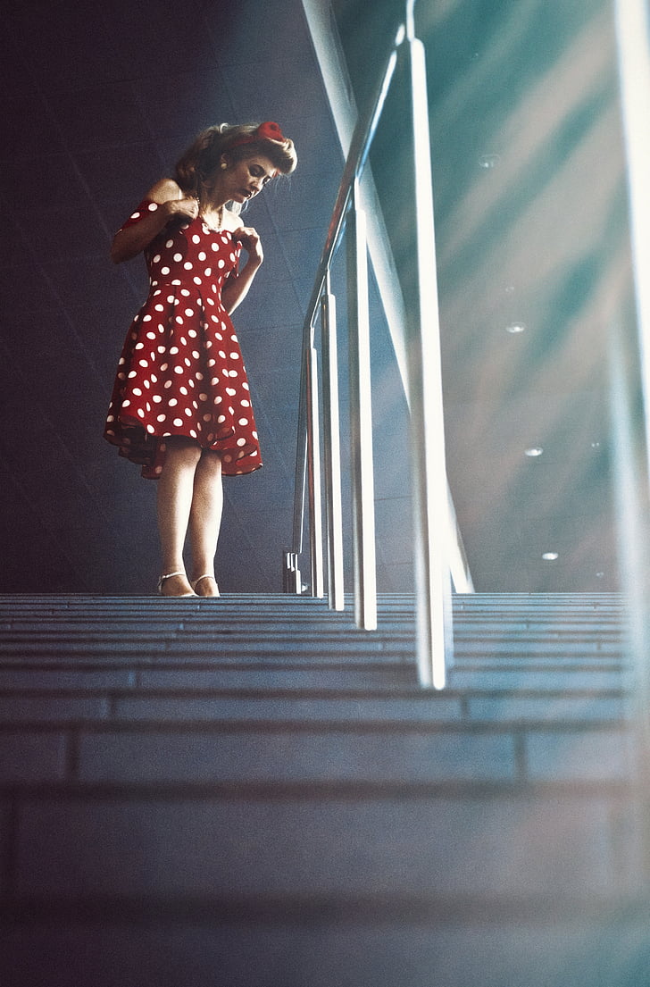 woman in white and red polka-dot dress near handrail