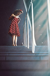 woman in white and red polka-dot dress near handrail