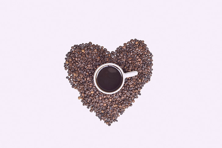 white ceramic mug on brown heart-shaped coffee beans