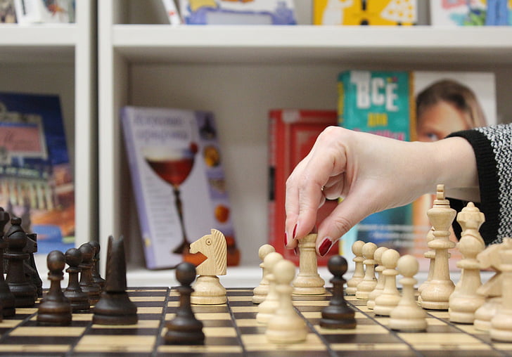 woman about to move chess rook