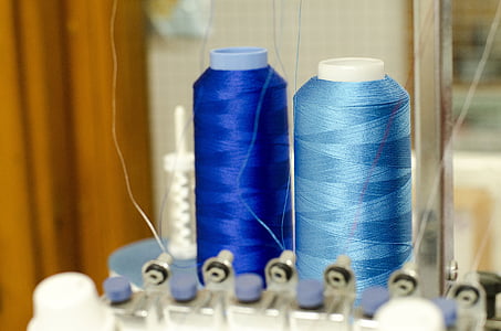 two blue and teal threads on interlocking machine