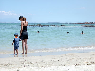 woman and child standing on seashore during daytime