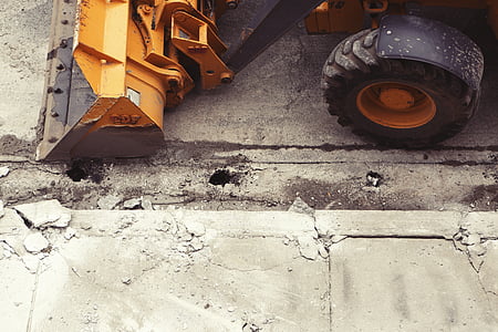 yellow excavator on gray concrete road