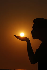 silhouette of a person as if he/she is summoning the sun on his/her hand