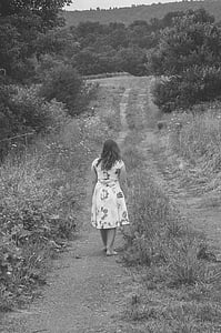 grayscale photography of barefooted woman walking on pathway surrounded by trees