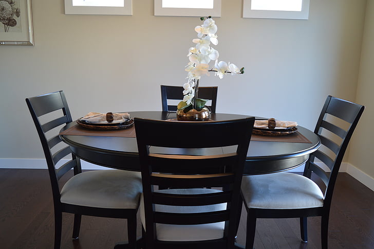 round brown wooden table with four chairs inside room