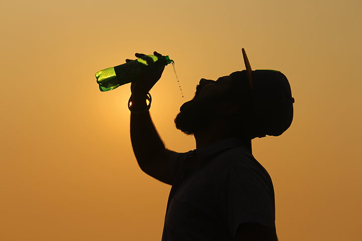 silhouette of man drinking during sunset