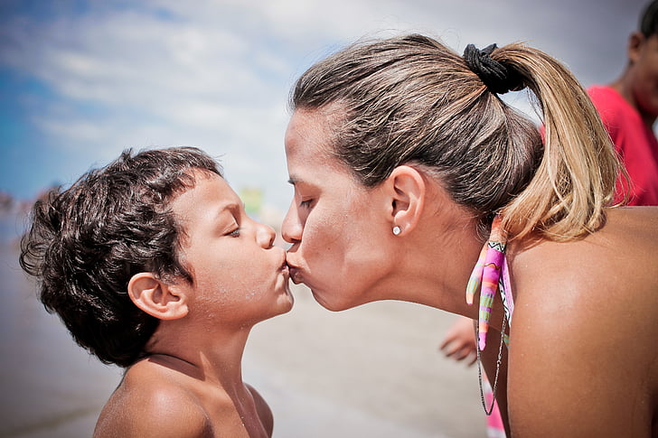 woman kissing boy in shallow focus lens